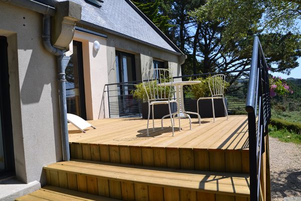 Terrasse en bois sur pilotis avec garde-corps en ferronnerie.